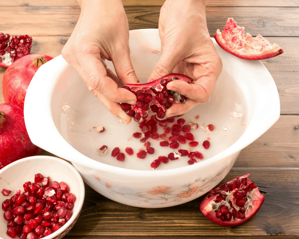 removing pomegranate seeds in bowl of water
