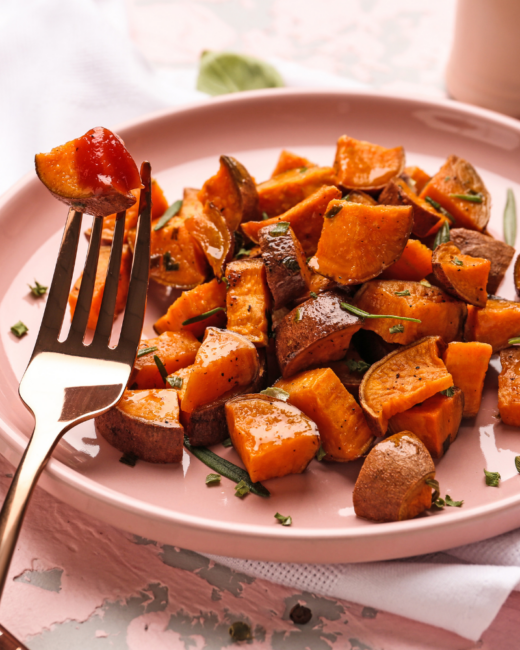 diced sweet potatoes on a pink plate with herbs. 