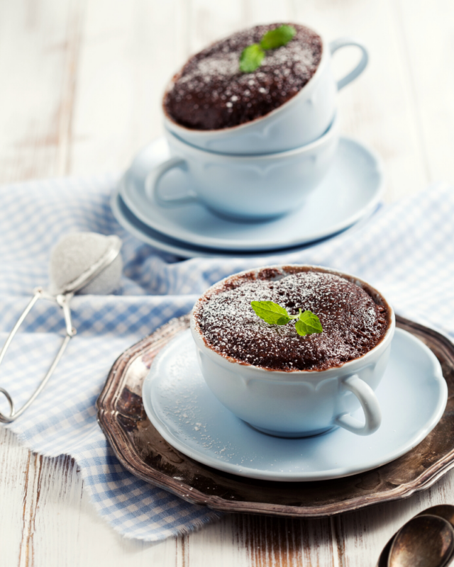 two chocolate cakes in blue mugs. 