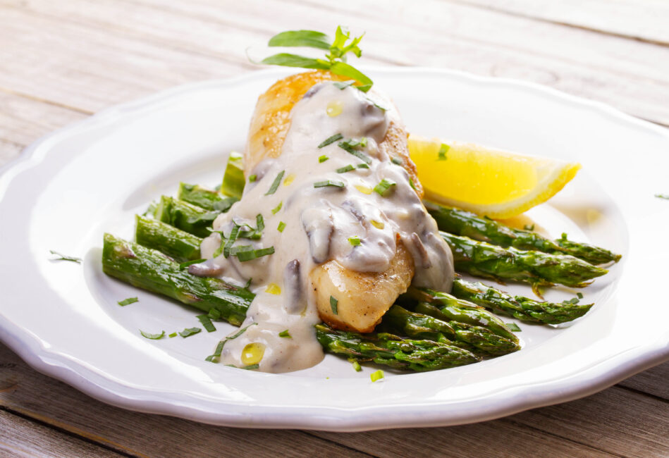 Fried chicken breast on asparagus with tarragon dressing
