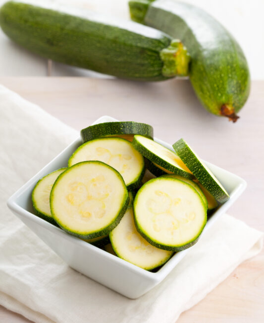 Fresh organic zucchini sliced in bowl on wooden table